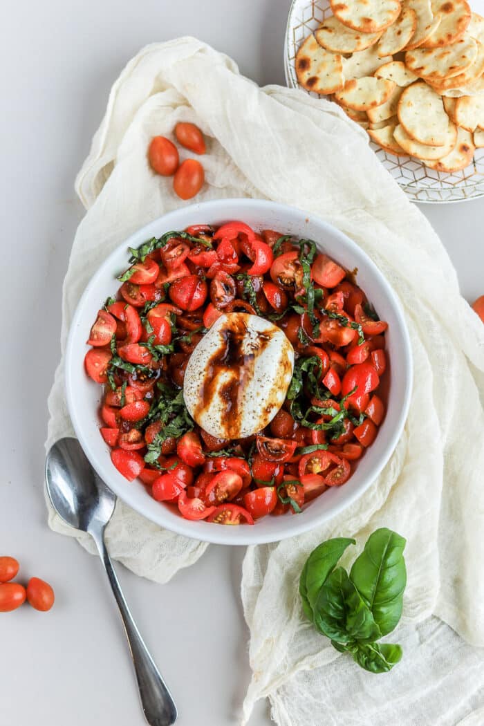 This burrata caprese appetizer is so simple, and so delicious. The creamy burrata cheese on top of marinated fresh tomatoes topped with fresh basil leaves and a balsamic reduction will be your new favorite recipe!