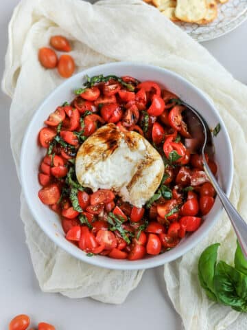 This burrata caprese appetizer is so simple, and so delicious. The creamy burrata cheese on top of marinated fresh tomatoes topped with fresh basil leaves and a balsamic reduction will be your new favorite recipe!