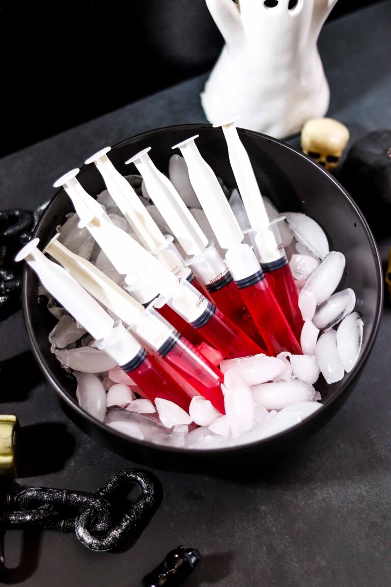 Red syringe jello shots filled with cherry Jell-O and tequila, served on ice for Halloween